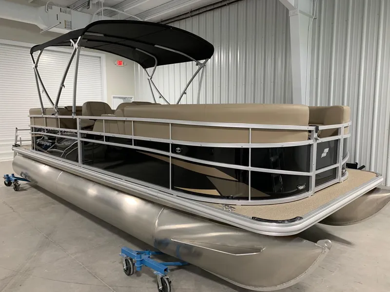 Slide: The Image of 2024 Starcraft LX22 R pontoon boat with black and beige design in a showroom. - 3