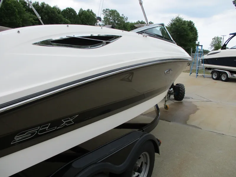 Slide: The Image of A 2013 Sea Ray 210 SLX boat on a trailer, surrounded by trees. - 22