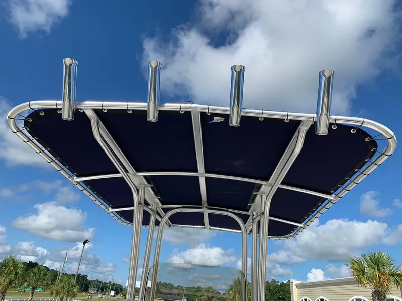 Slide: The Image of 2024 Robalo R202 Explorer T-top with rod holders against a blue sky. - 7