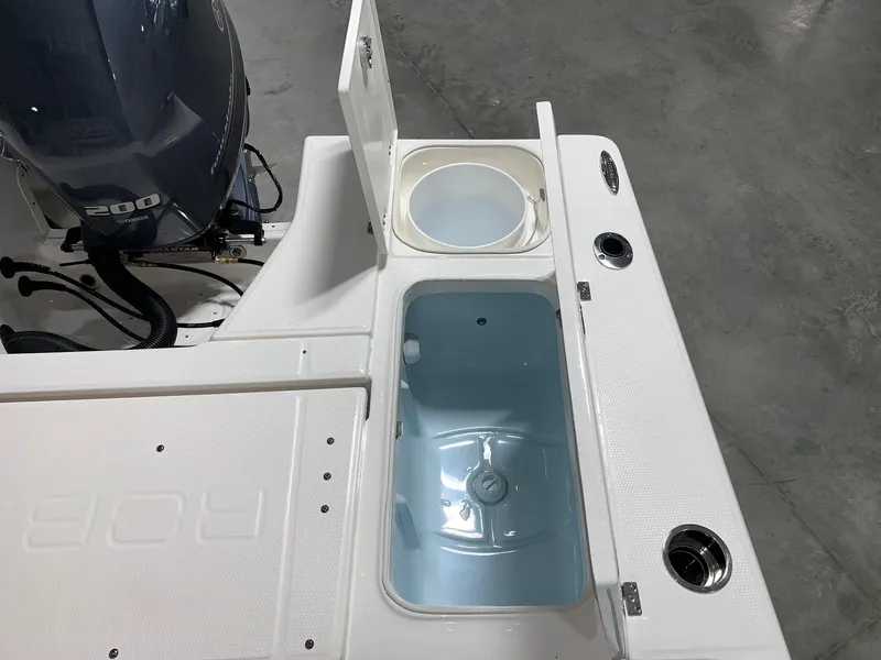 Slide: The Image of 2024 Robalo 226 Cayman boat with open storage compartments and outboard motor. - 9