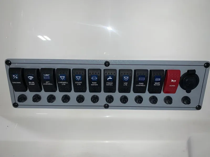 Slide: The Image of Control panel of a 2024 Key West 250 Bay Reef boat with various switches. - 23