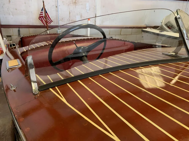 Slide: The Image of 1947 Chris-Craft 17 Runabout Deluxe with wooden deck and American flag in background. - 18