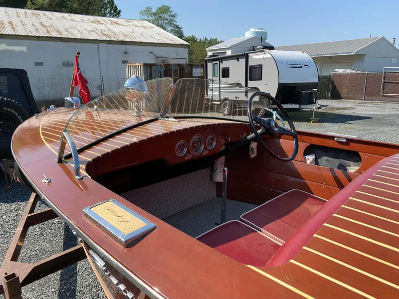 Slide: The Image of 1947 Chris-Craft 17 Runabout Deluxe boat with wooden finish and red interior, parked outdoors. - 28