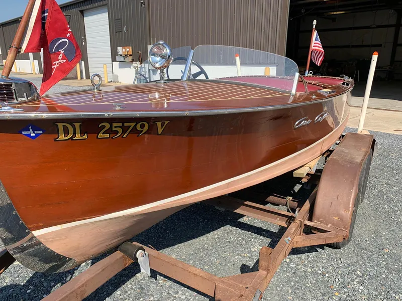 Slide: The Image of 1947 Chris-Craft 17 Runabout Deluxe wooden boat on trailer, featuring classic design and flags. - 3