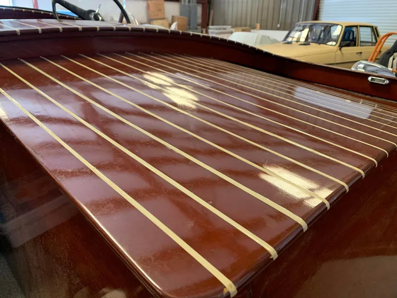 Slide: The Image of 1947 Chris-Craft 17 Runabout Deluxe with polished wooden deck in a garage setting. - 8