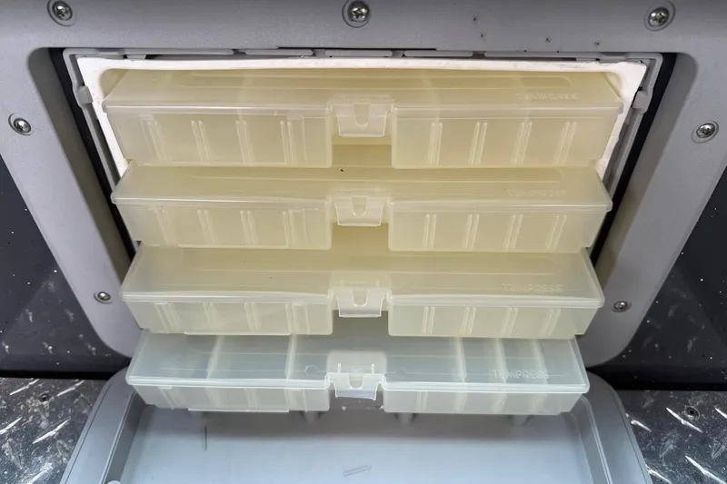 Slide: The Image of Tackle storage compartment in a 2019 Fish Rite Stalker boat, featuring organized plastic boxes. - 42