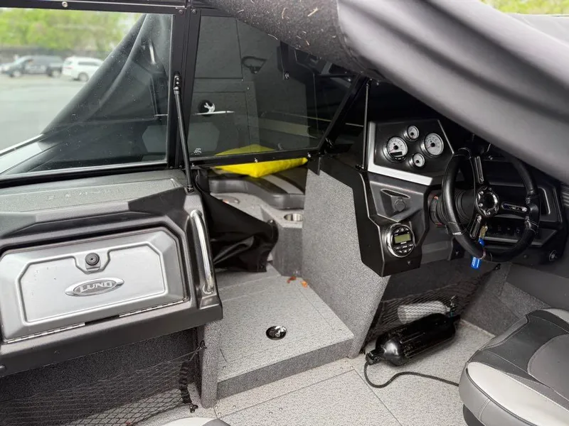 Slide: The Image of Interior of a 2021 Lund 1975 Tyee boat, featuring steering wheel and dashboard controls. - 16