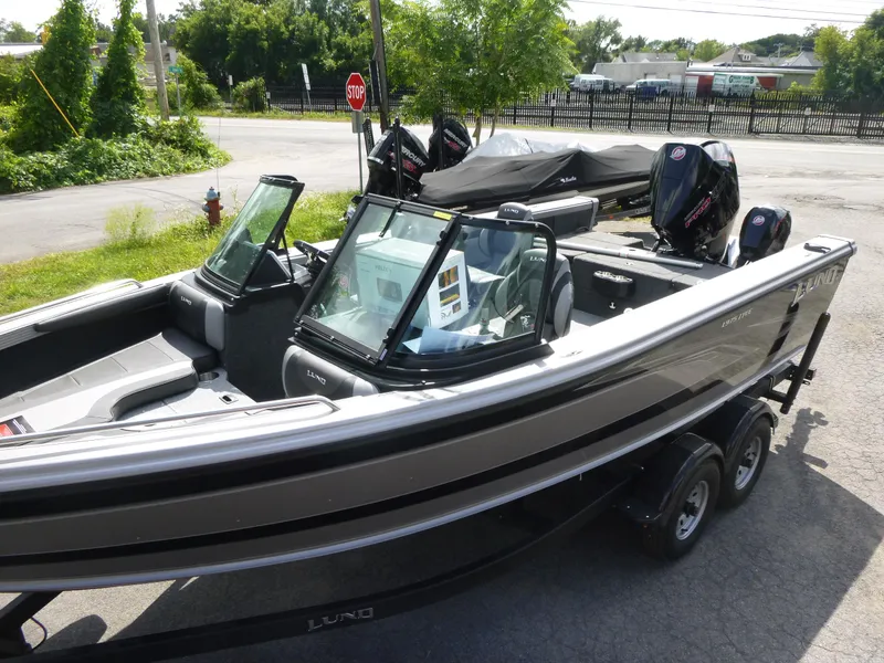 Slide: The Image of 2021 Lund 1975 Tyee boat with dual motors, parked outdoors on a trailer. - 24