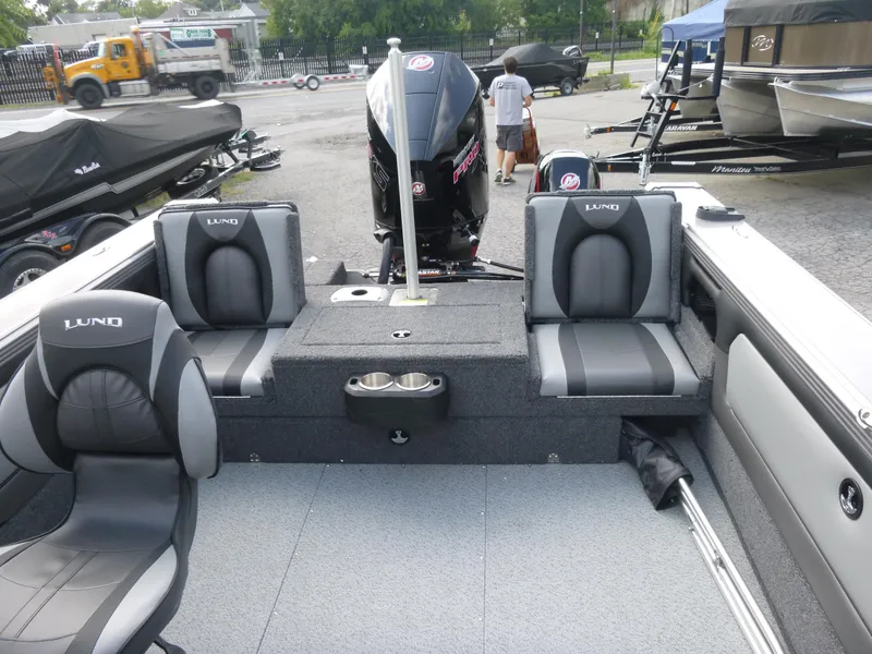 Slide: The Image of 2021 Lund 1975 Tyee boat interior with seating and motor, parked outdoors. - 28