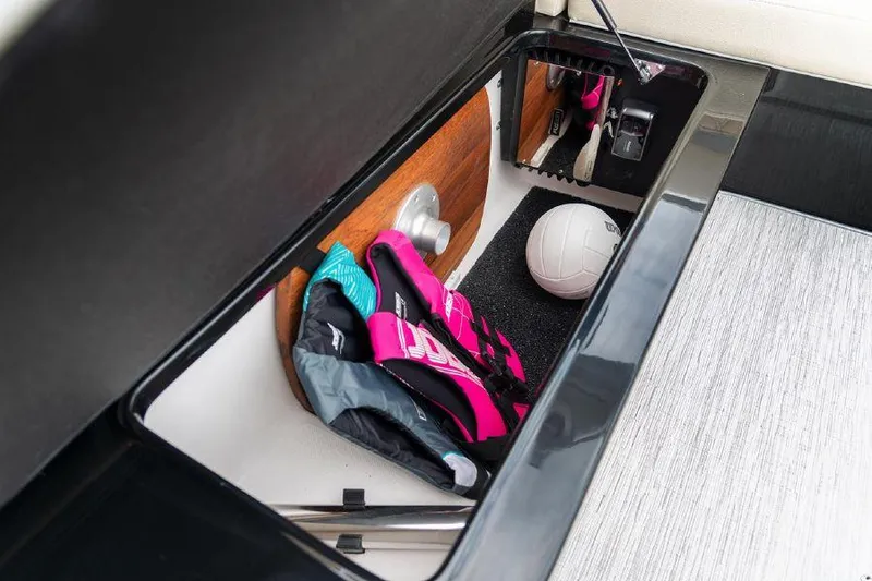 Slide: The Image of 2023 Regal 2800 Bowrider storage compartment with life jackets and volleyball. - 18