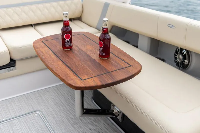 Slide: The Image of 2023 Regal 2800 Bowrider interior with wooden table and two bottles, beige seating. - 6
