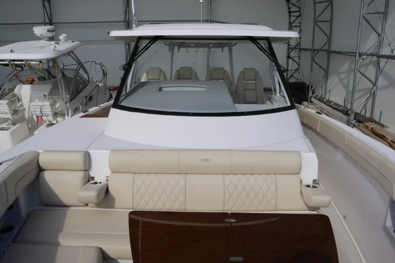 Slide: The Image of 2023 Regal 38 SAV luxury boat with spacious seating and sleek design in a marina setting. - 11