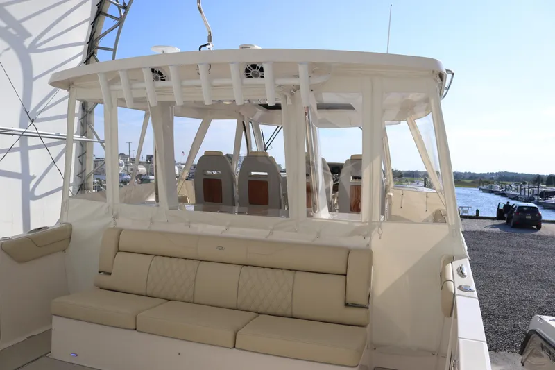 Slide: The Image of 2023 Regal 38 SAV boat with beige seating, docked at a marina under clear skies. - 45