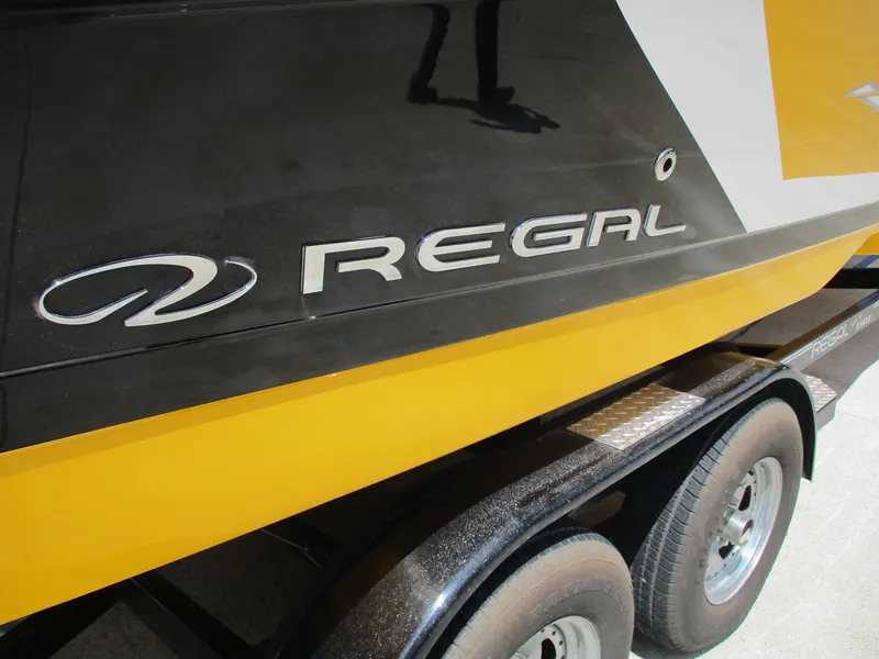 Slide: The Image of 2013 Regal 24 FasDeck RX boat on trailer, featuring sleek black and yellow design. - 4