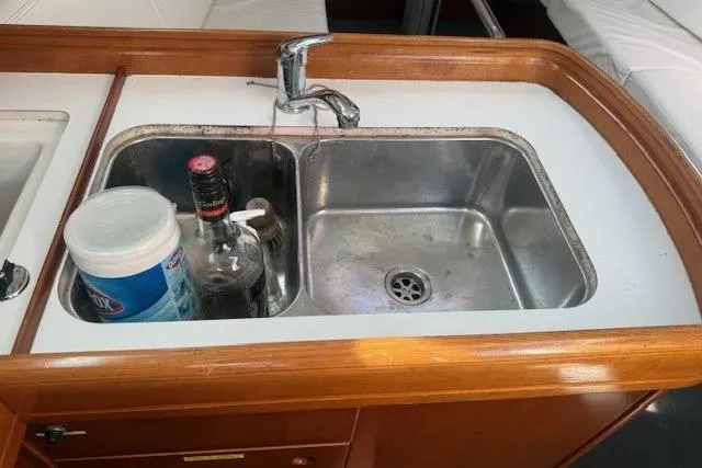 Slide: The Image of Beneteau First 36.7 yacht kitchen sink with faucet, cleaning supplies, and bottles, 2002 model. - 20