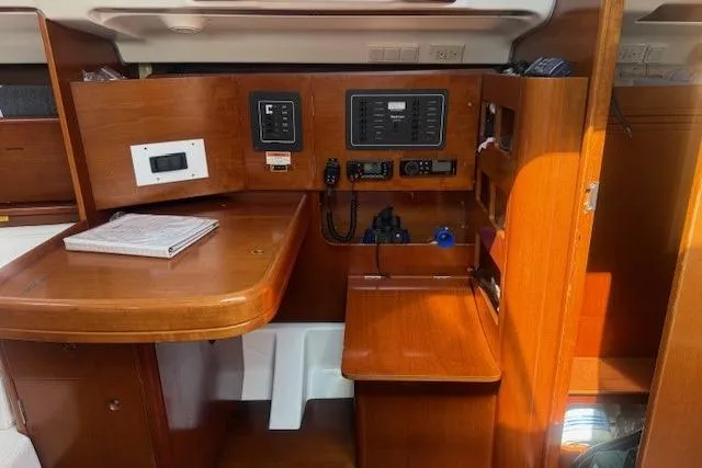 Slide: The Image of Navigation station inside 2002 Beneteau First 36.7 sailboat with wooden cabinetry and control panels. - 22