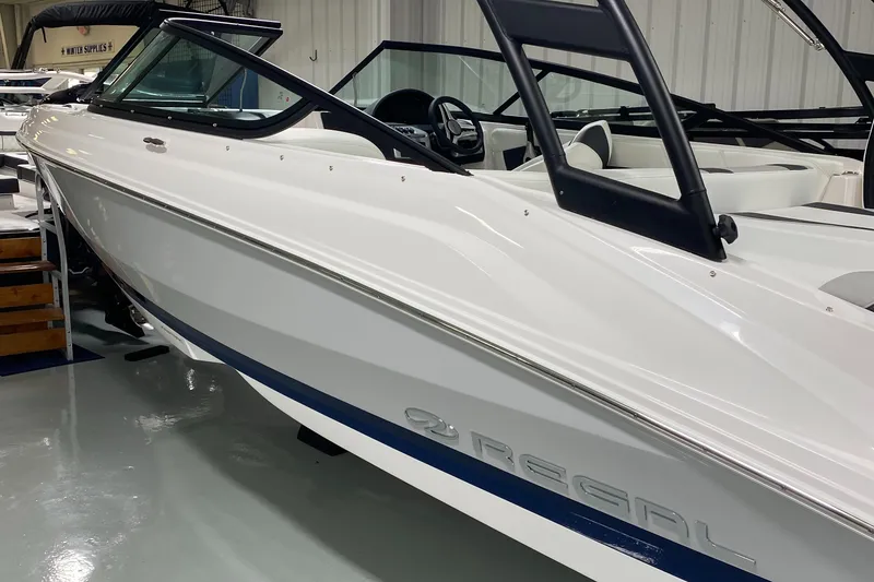 Slide: The Image of 2022 Regal 21 OBX boat in showroom, sleek white design with blue accents. - 3