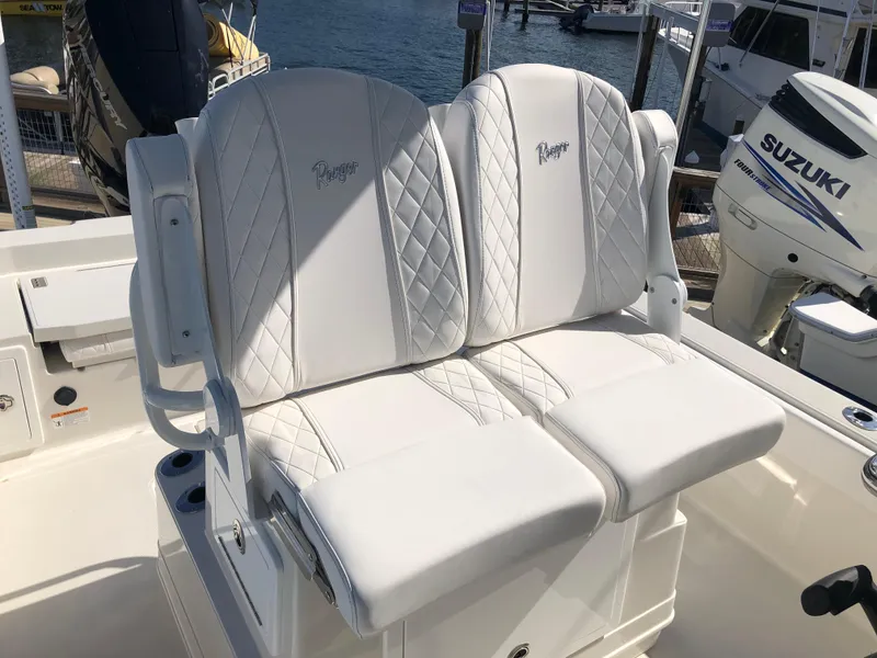 Slide: The Image of 2025 Ranger 2660 boat seats with quilted white upholstery, docked near Suzuki engine. - 27