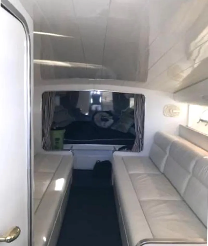 Slide: The Image of Interior of a 1999 Custom 42 boat with white leather seating and cozy cabin space. - 10