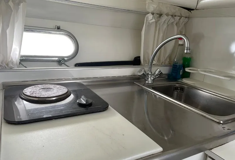 Slide: The Image of Compact kitchen in a 1999 Custom 42 boat with stove, sink, and window. - 16