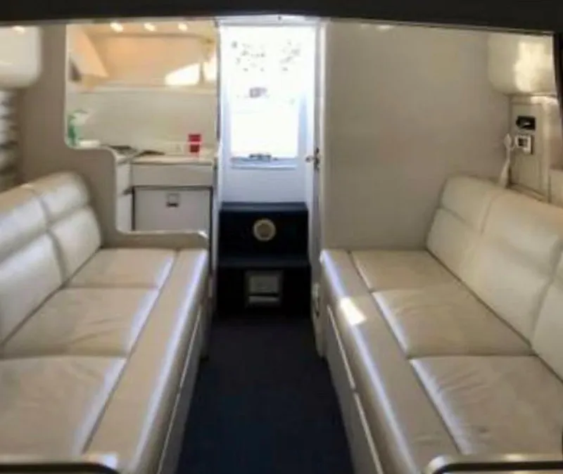 Slide: The Image of Interior of a 1999 Custom 42 model with white leather seating and compact kitchen area. - 9