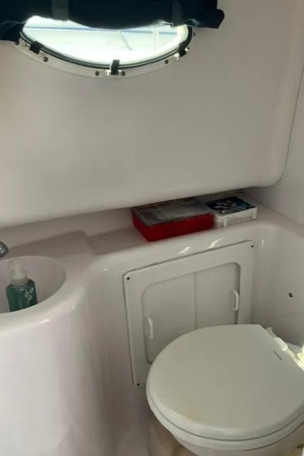 Slide: The Image of 2004 Pro-Line 30 WALK boat bathroom with toilet, sink, and porthole window. - 8