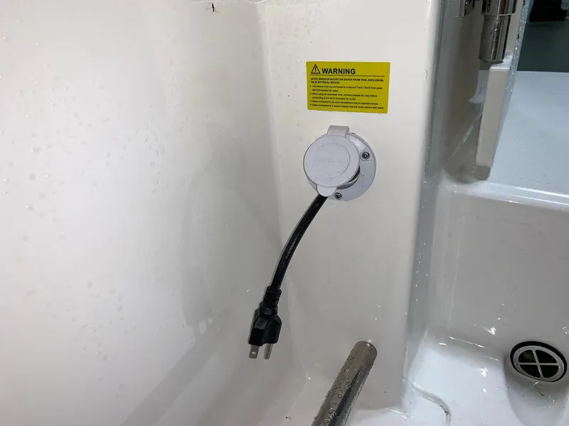 Slide: The Image of 2026 Robalo R222 Center Console boat power outlet with warning label. - 25