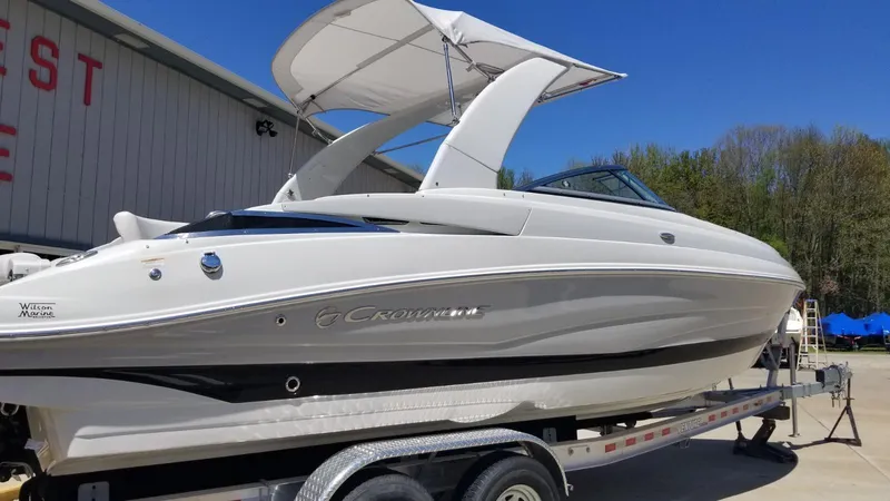 Slide: The Image of 2018 Crownline 275 SS boat on trailer, featuring sleek design and canopy, parked outdoors. - 2