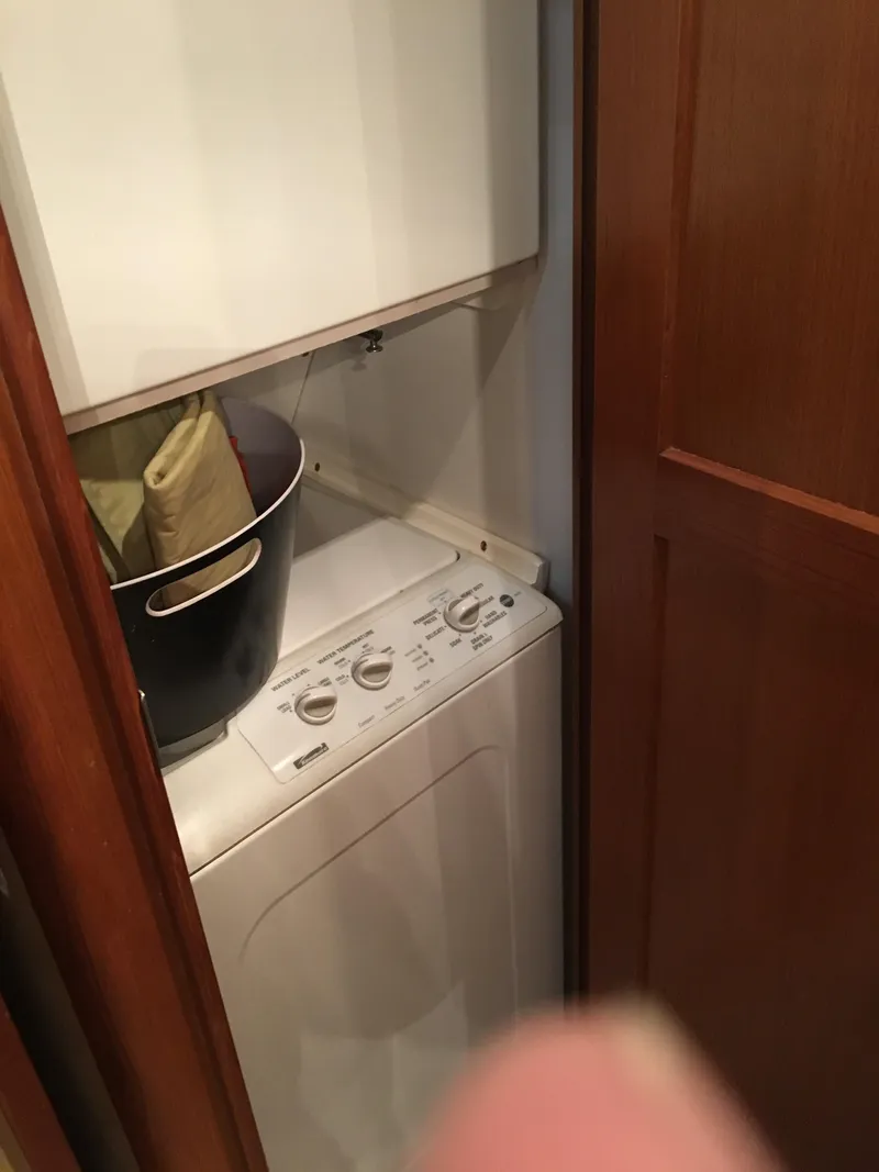 Slide: The Image of Laundry area inside 2001 Ocean Yachts 56 Super Sport, featuring a compact washer and dryer. - 26
