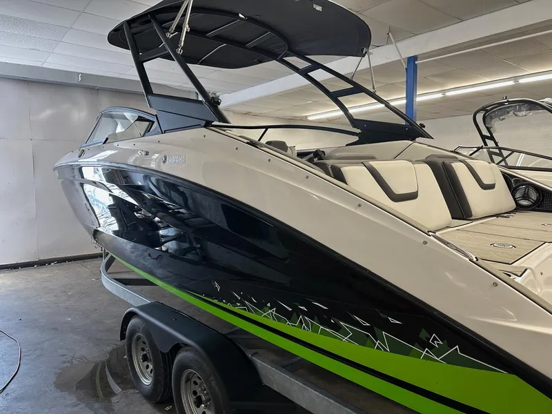 Slide: The Image of 2021 Yamaha Boats AR250 with sleek black and green design in showroom. - 3