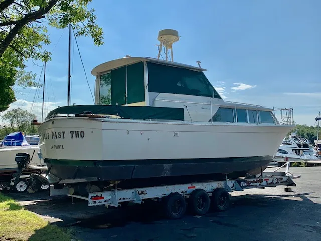 The Image of 1969 Chris-Craft Commander Sedan boat on trailer, parked outdoors under clear sky. - 0