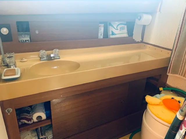 Slide: The Image of 1969 Chris-Craft Commander Sedan bathroom with beige sink, wooden cabinetry, and toiletries. - 18