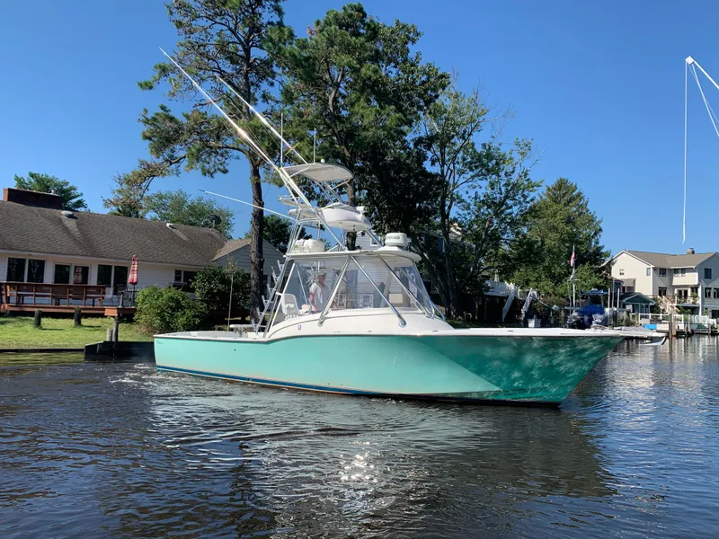 The Image of 2003 L&H 33 boat on calm water near houses. - 0