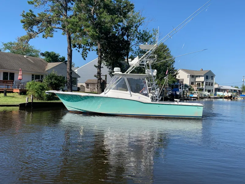 Slide: The Image of 2003 L&H 33 boat on calm water near houses. - 2
