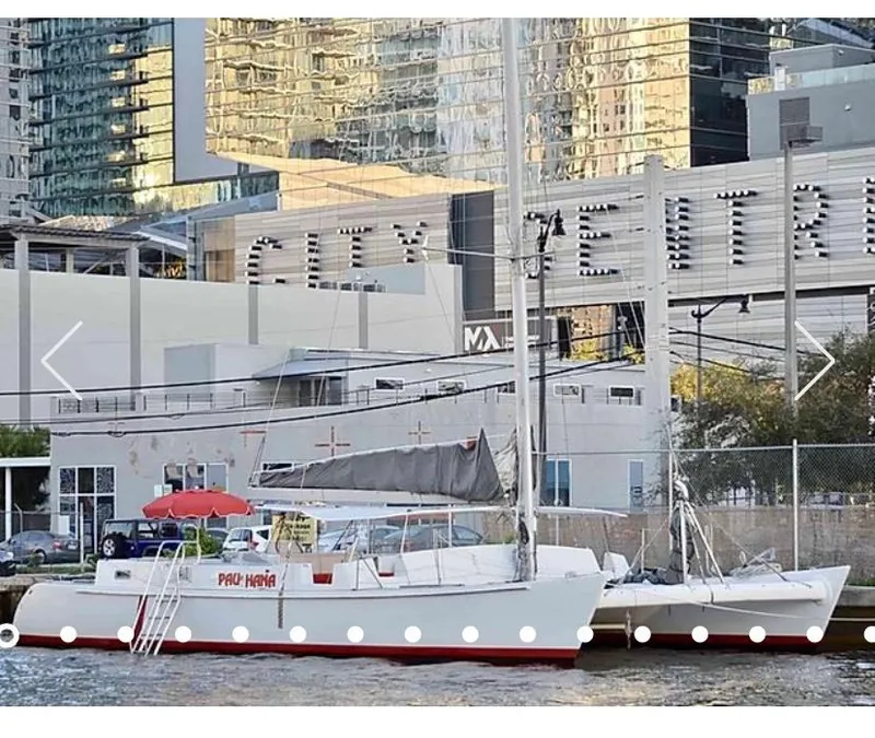 The Image of 1987 Custom Suncoast Catamaran docked near city buildings, featuring a red umbrella. - 0