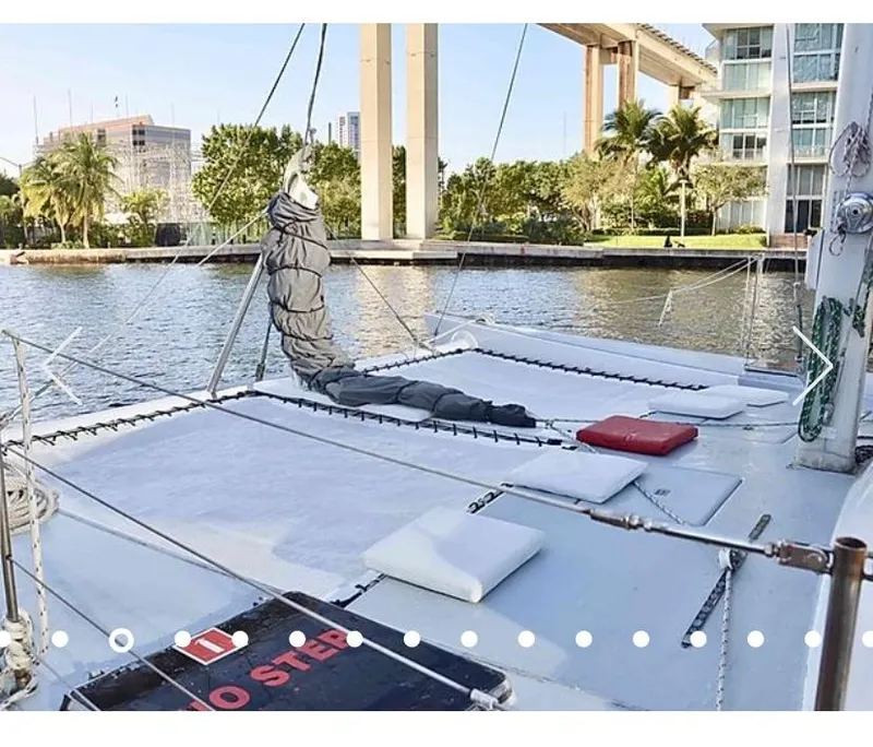 Slide: The Image of 1987 Custom Suncoast Catamaran docked by waterfront with lush greenery and modern buildings. - 6
