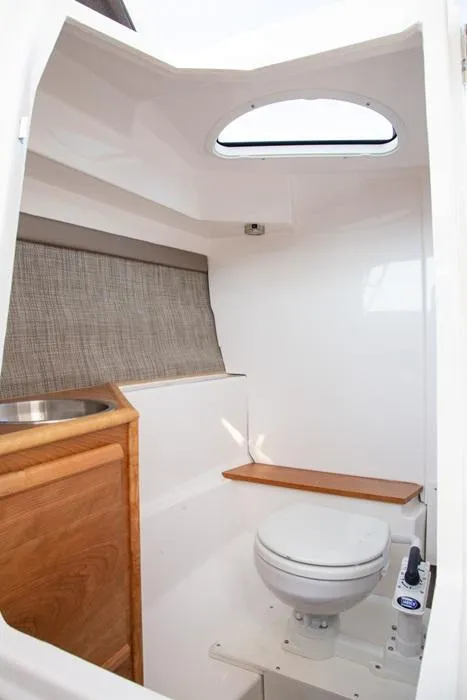 Slide: The Image of 2020 Cutwater 24 DC boat interior with compact bathroom and wooden accents. - 11