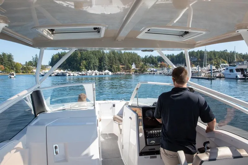 Slide: The Image of Man steering 2020 Cutwater 24 DC boat in scenic marina. - 4