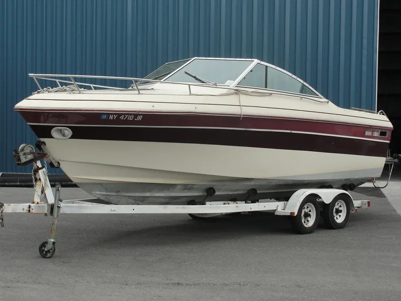 Slide: The Image of 1987 Cobalt Condesa boat on a trailer, parked near a blue building. - 2