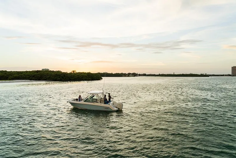 Slide: The Image of 2023 Boston Whaler 240 Vantage boat cruising on a serene lake at sunset. - 30