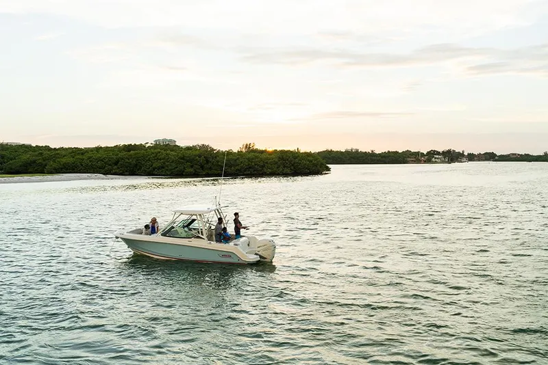 Slide: The Image of 2023 Boston Whaler 240 Vantage boat cruising on a serene lake at sunset. - 32