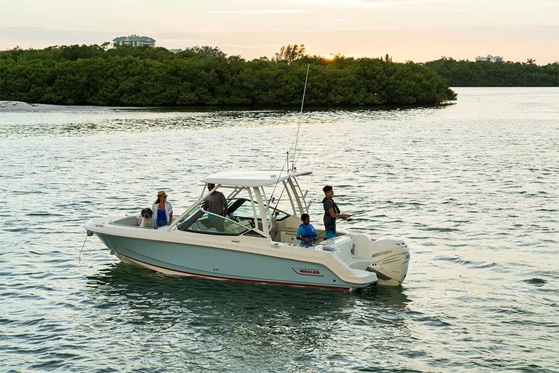 Slide: The Image of 2023 Boston Whaler 240 Vantage boat cruising on a serene lake at sunset. - 33