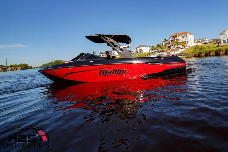 Slide: The Image of 2019 Malibu Wakesetter 25 LSV boat on water, red and black, sunny day. - 1