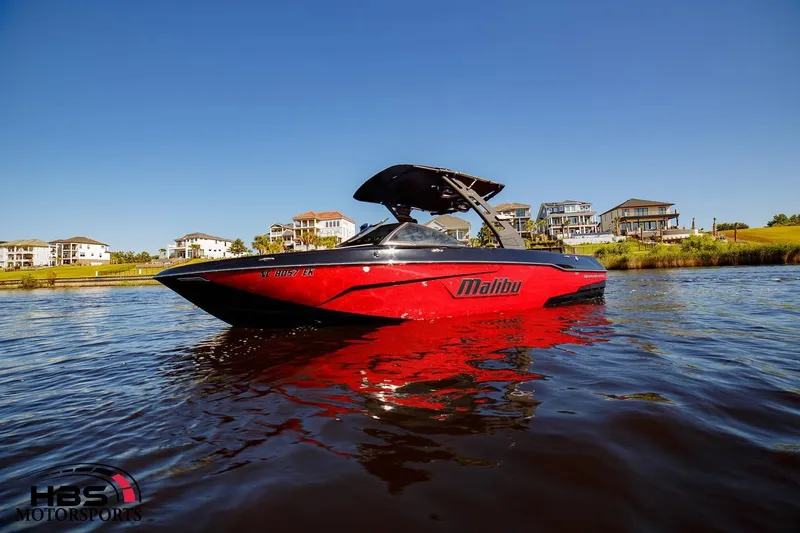 Slide: The Image of 2019 Malibu Wakesetter 25 LSV boat on water near waterfront homes. - 2