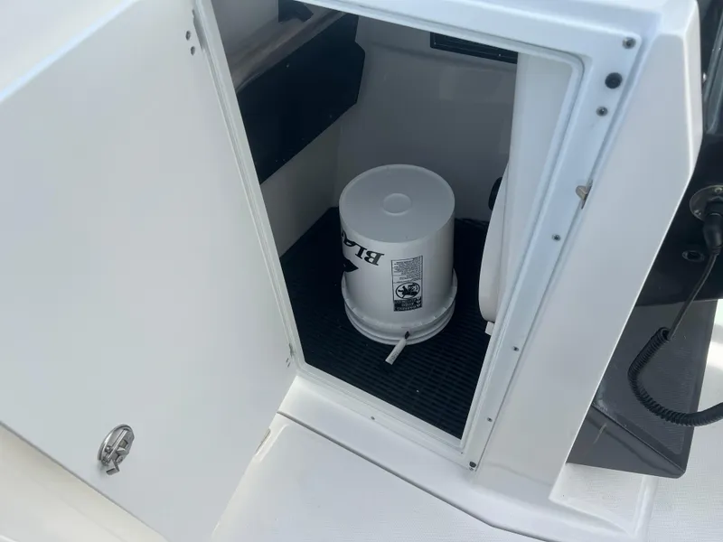 Slide: The Image of 2024 Blackfin 272DC storage compartment with a white bucket inside. - 21
