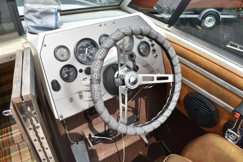 Slide: The Image of 1983 Rinker 204 Cuddy Cabin boat dashboard with steering wheel and gauges. - 12
