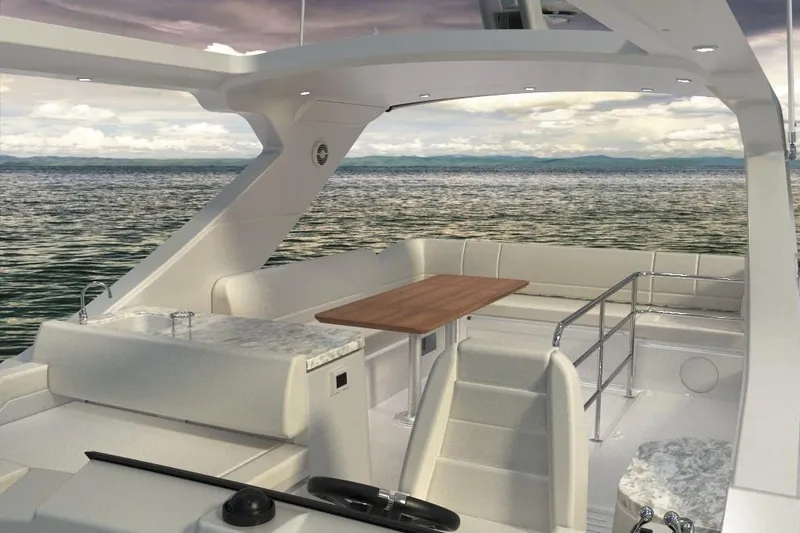 Slide: The Image of 2018 Sea Ray Fly 520 yacht interior with seating and table, overlooking calm waters. - 3