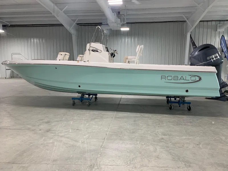 The Image of 2026 Robalo 226 Cayman boat in a showroom, side view, light blue hull. - 0