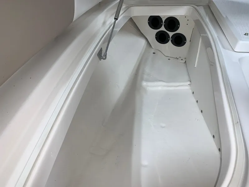 Slide: The Image of 2026 Robalo 226 Cayman boat storage compartment with rod holders and clean white interior. - 24