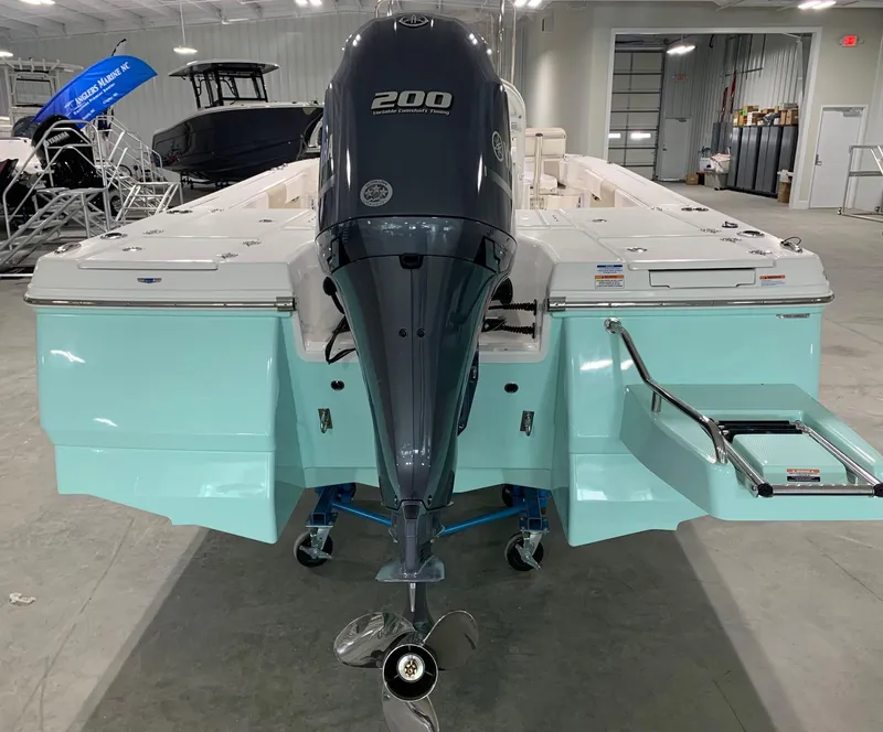 Slide: The Image of 2026 Robalo 226 Cayman boat with a 200 HP engine in a showroom. - 2